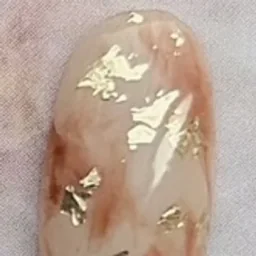 アイボリーとブラウンのマーブルに金色の箔を散らしたネイルの実物写真